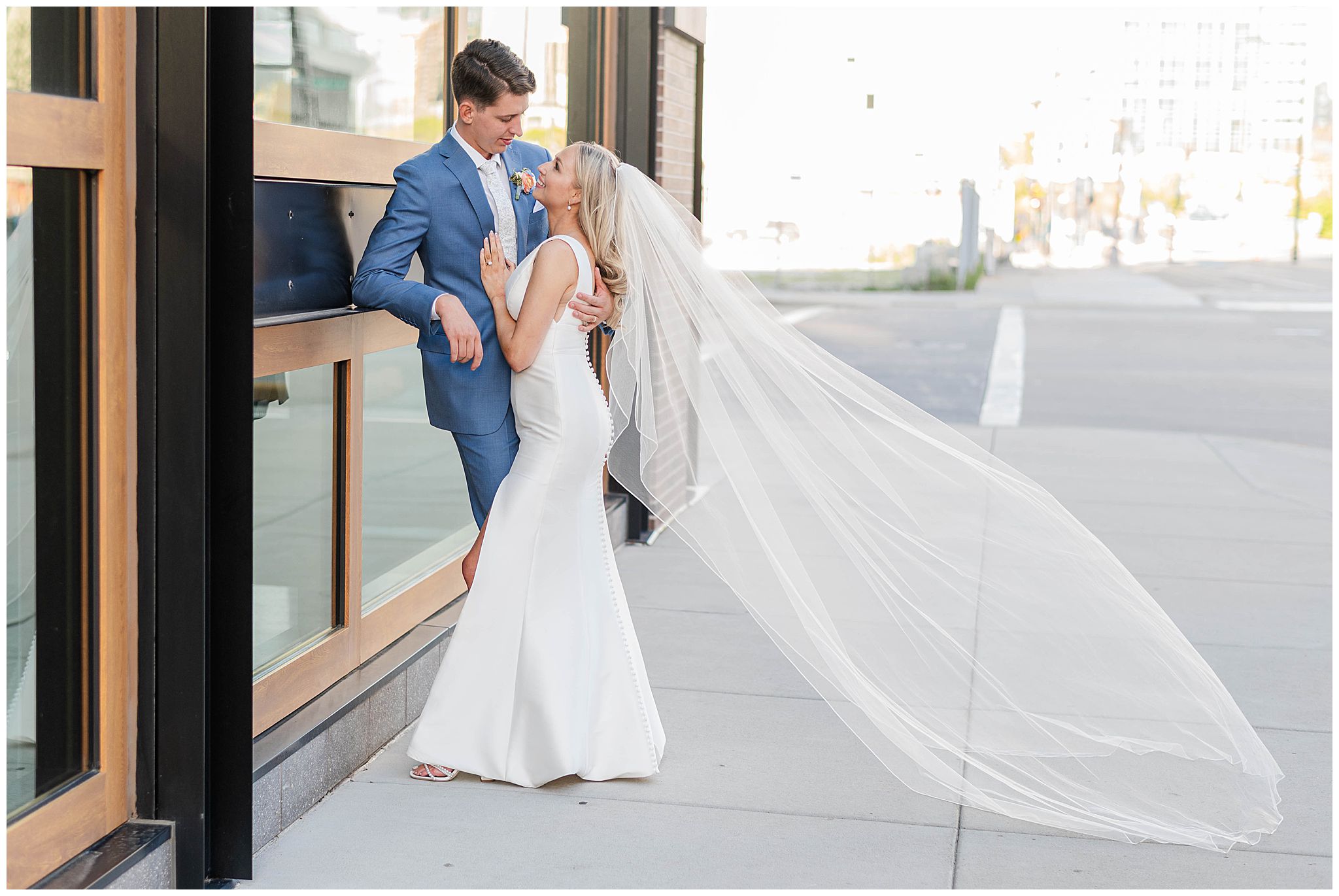 A golden hour portrait of the bride and groom snuggled up together as her long veil flows behind her on their wedding day in Milwaukee.