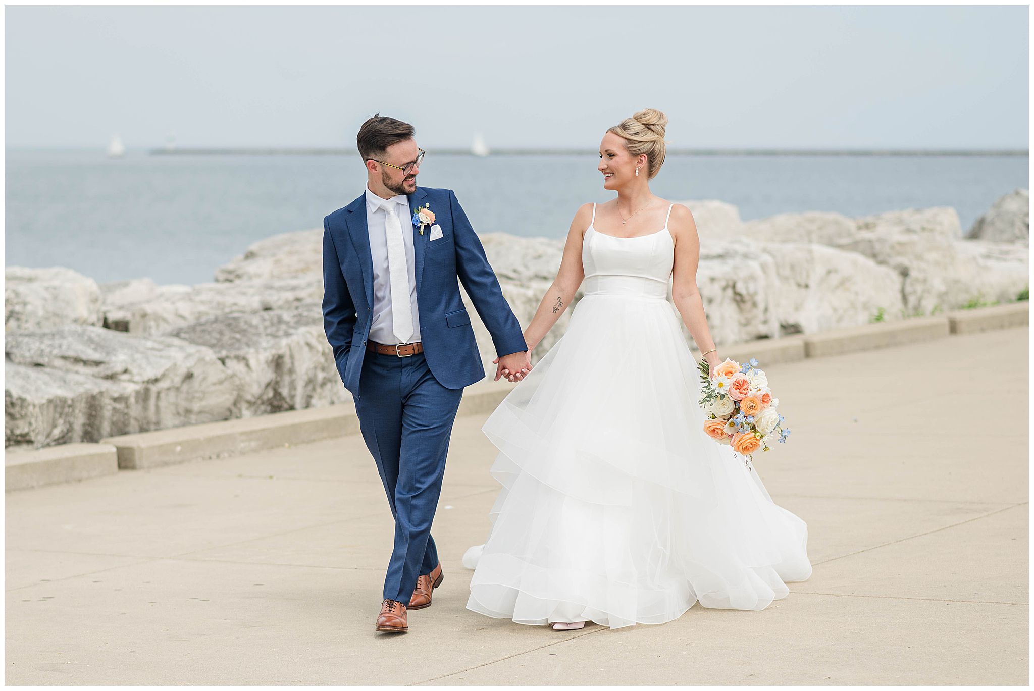 Bride and groom walking along side Lake Michigan on their wedding day in Milwaukee, WI, take by Taylor Kelley Photography.